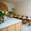 Super-Seat | Cafe Interior | A cafe with brown/oak wooden chairs and white round tables, a marble counter, white walls and a mottled floor. | Hospitality Furniture
