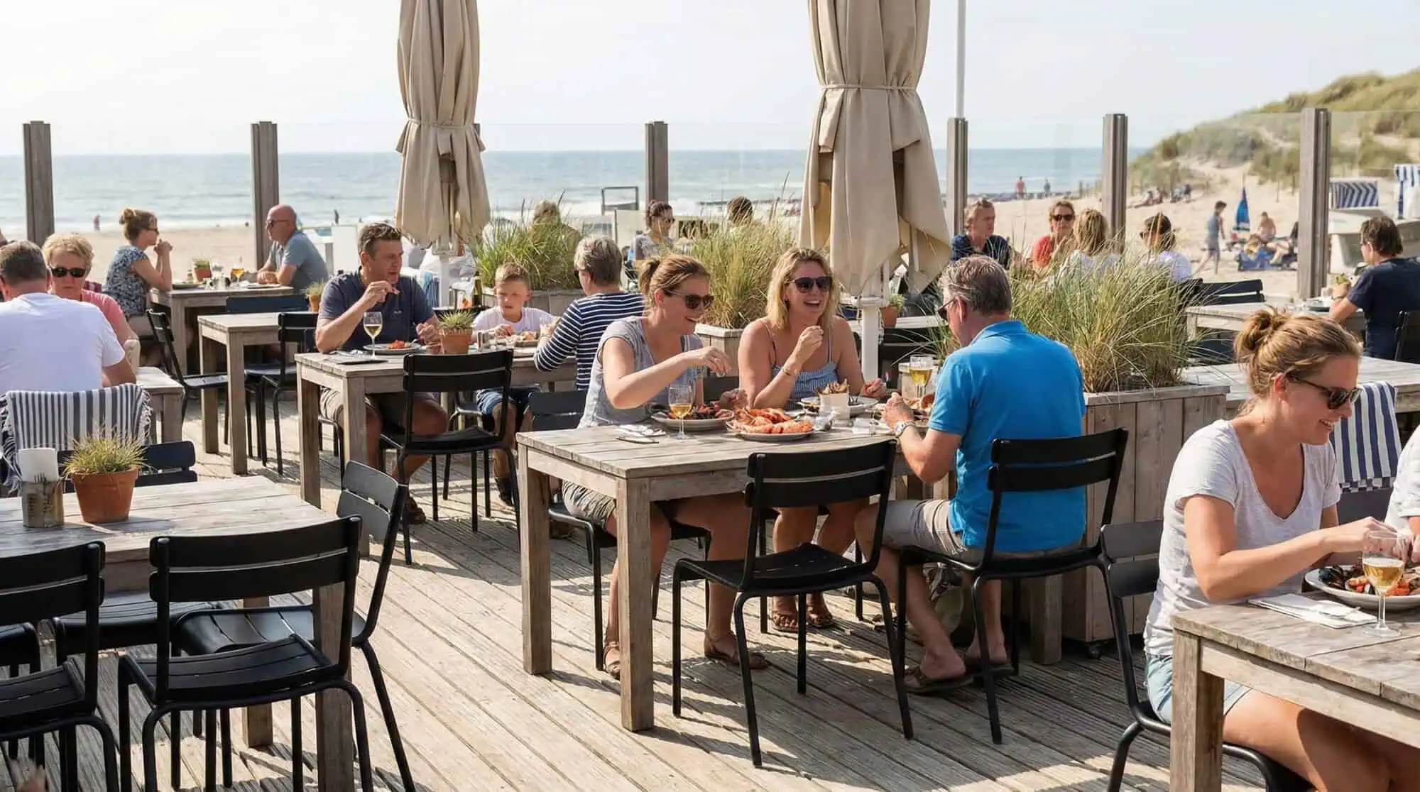 Super-Seat | Luxury Terrace Furniture by the Sea | Black metal stacking chairs, wooden tables on terrace with sea view and sand dunes, lively atmosphere. | Hospitality Furniture