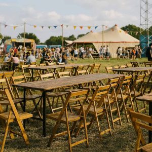 Super-Seat | Rijen lege Berlijn vintage houten klaptafels naturel 200x50cm en stoelen | Lichtbruine houten klaptafels en stoelen van hout, naturel kleur, op gras in de buitenlucht. | Horecameubilair