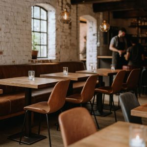 Super-Seat | Ein modernes Restaurantinterieur mit Holztischen, cognacfarbenen Lederstühlen, Glasakzenten, Backsteinwänden und Pendelleuchten. |. | Horecameubilair