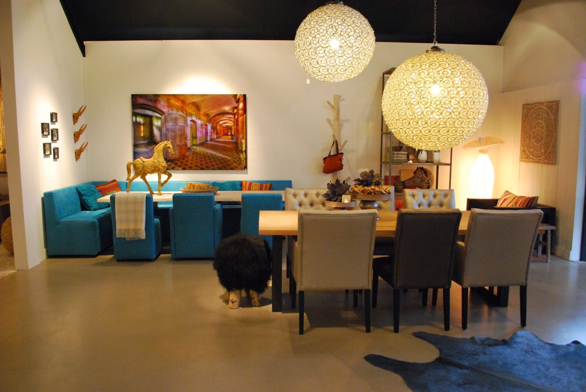 Super-Seat | A modern living and dining room | Table: wood, mixed seating; Crystal chandelier; Blue sofa; Decorative accents. | Hospitality Furniture