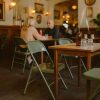 Super-Seat | FieldFold Vintage-Klappstühle aus Metall in Armeegrün | Groene metalen klapstoelen, houten tafel, bruine fles met droogplant, glazen. | Horecameubilair