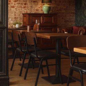 Super-Seat | Jody hospitality design chairs black/brown | Black and brown stackable chairs made of wood/leather, wooden tables, leather bench, brick wall. | Hospitality Furniture
