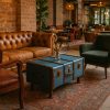Super-Seat | Brown leather sofa, green fabric armchair, blue wooden trunk table, melange rug. | Hospitality Furniture